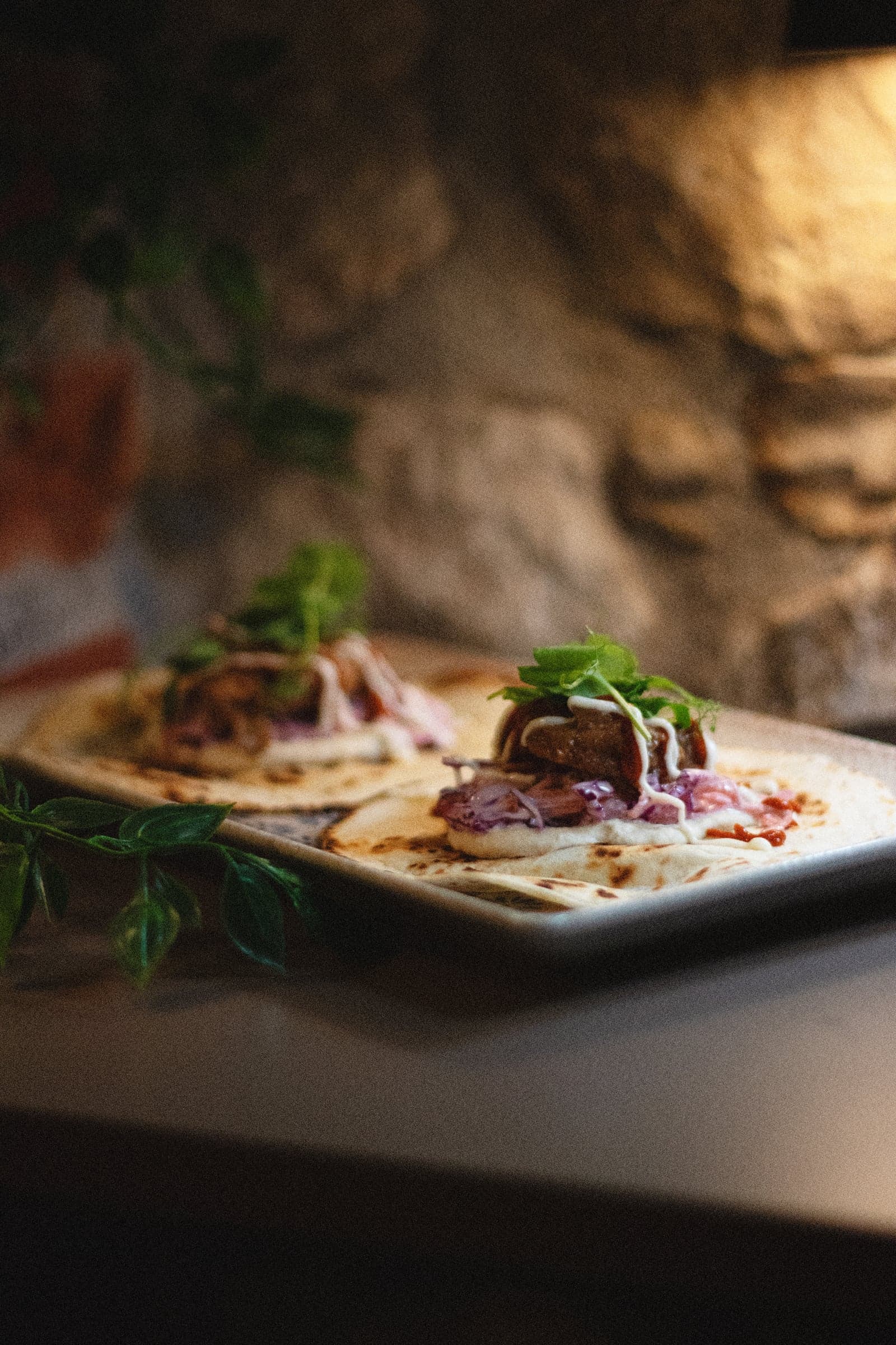 Tacos on tray with stone wall backdrop